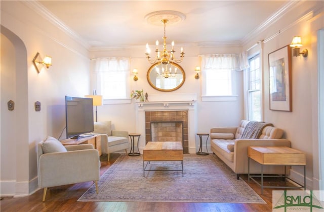 living area with an inviting chandelier, arched walkways, plenty of natural light, and wood-type flooring