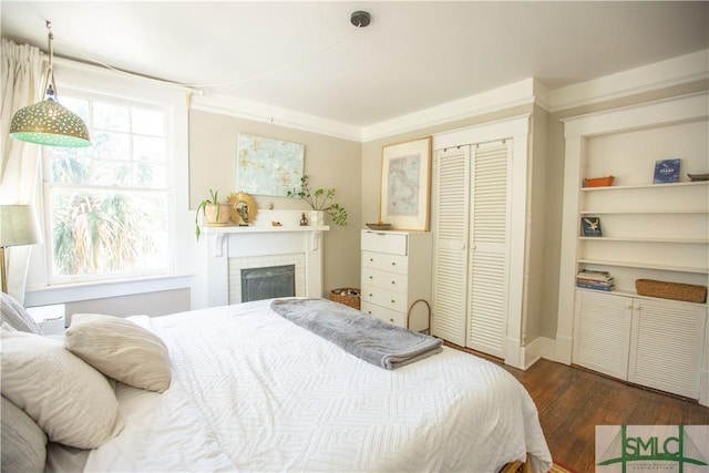 bedroom featuring a closet, baseboards, dark wood-style floors, and a fireplace