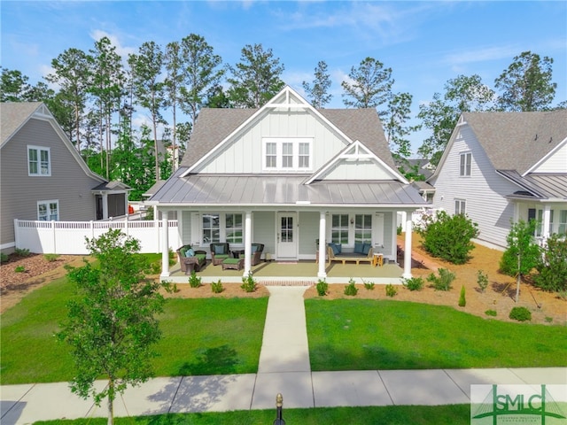 view of front facade with fence, a front yard, a standing seam roof, an outdoor living space, and board and batten siding