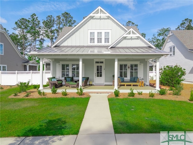 view of front facade with a standing seam roof, board and batten siding, an outdoor living space, and a front lawn