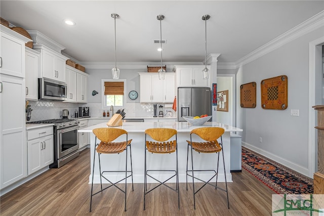 kitchen with appliances with stainless steel finishes, a breakfast bar, white cabinetry, backsplash, and ornamental molding