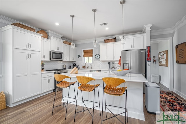 kitchen featuring visible vents, wood finished floors, white cabinets, and stainless steel appliances