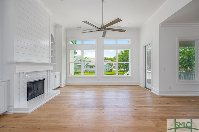 unfurnished living room with ornamental molding, a fireplace, a ceiling fan, and a wealth of natural light