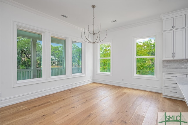 unfurnished dining area featuring crown molding, a chandelier, plenty of natural light, and light wood-type flooring