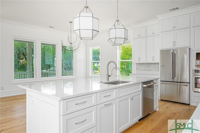 kitchen featuring visible vents, an island with sink, light countertops, a sink, and stainless steel appliances
