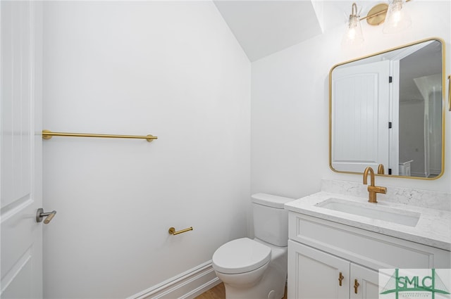 half bathroom featuring vanity, toilet, wood finished floors, and lofted ceiling