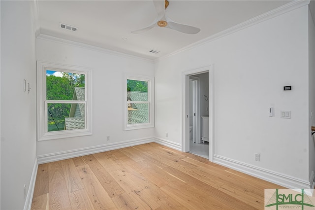 empty room with crown molding, ceiling fan, light wood-style floors, and visible vents