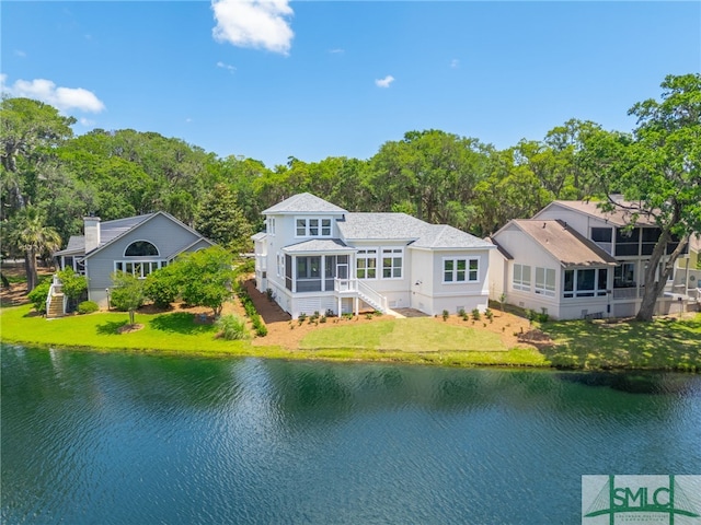 back of property with a sunroom, a water view, a yard, and stairs
