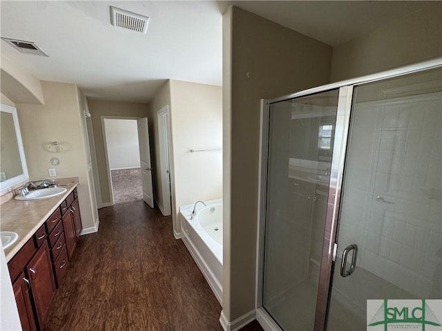 full bathroom with visible vents, a sink, wood finished floors, and a stall shower
