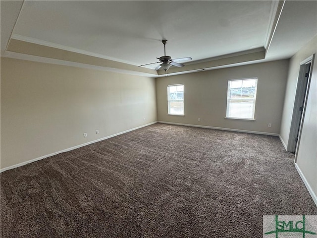empty room featuring crown molding, a raised ceiling, carpet, a ceiling fan, and baseboards