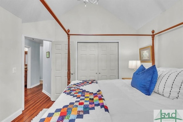bedroom with a closet, baseboards, vaulted ceiling, and wood finished floors