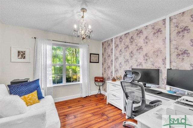 office area with baseboards, a textured ceiling, wood finished floors, and a notable chandelier