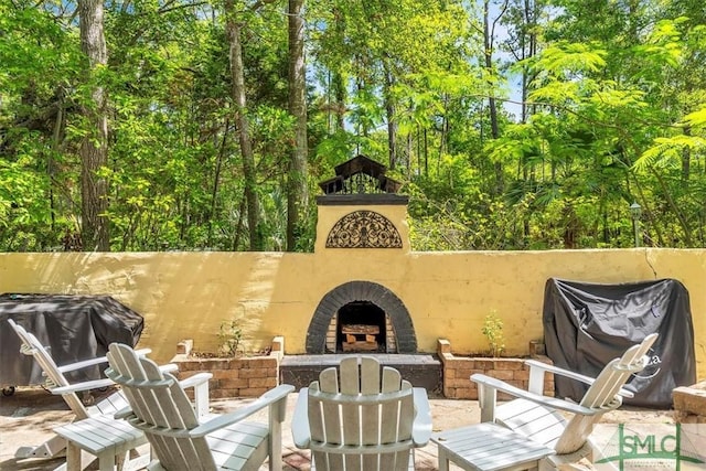 view of patio featuring an outdoor brick fireplace and grilling area