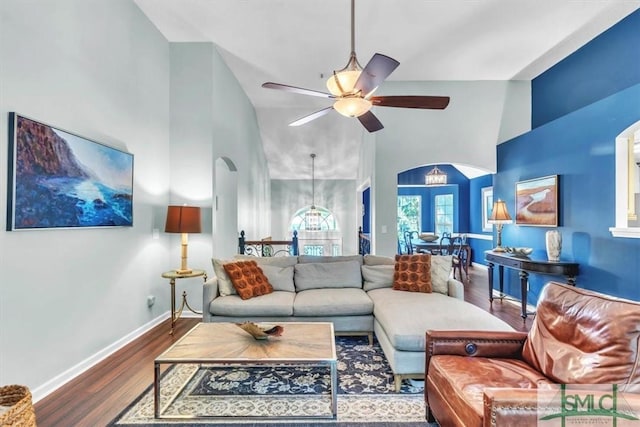 living room with arched walkways, baseboards, ceiling fan with notable chandelier, and wood finished floors