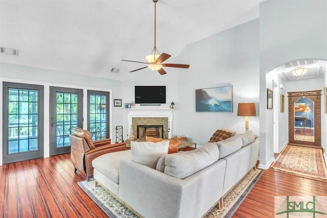 living area with visible vents, a fireplace, hardwood / wood-style flooring, a ceiling fan, and vaulted ceiling