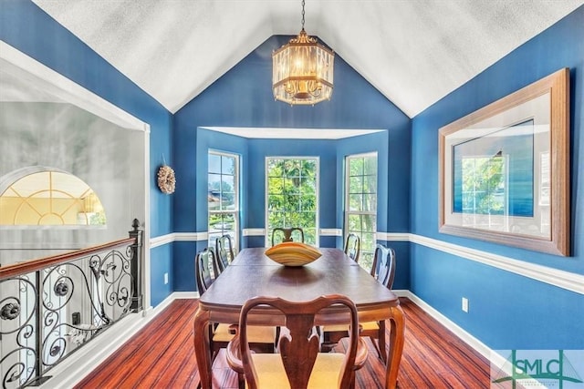 dining room featuring baseboards, wood finished floors, a chandelier, and vaulted ceiling