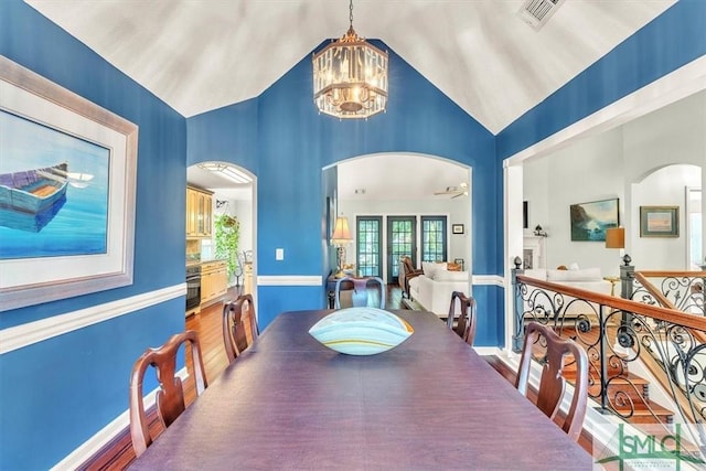 dining area featuring arched walkways, a notable chandelier, visible vents, and high vaulted ceiling