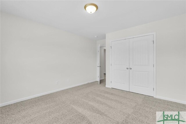 unfurnished bedroom with baseboards, carpet, and a closet