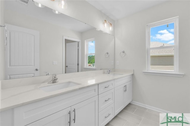 bathroom featuring baseboards, a sink, tile patterned floors, and double vanity