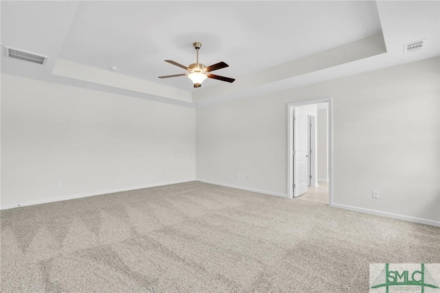 unfurnished room with ceiling fan, visible vents, light carpet, and a raised ceiling