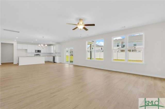 unfurnished living room featuring visible vents, baseboards, light wood-type flooring, recessed lighting, and ceiling fan with notable chandelier
