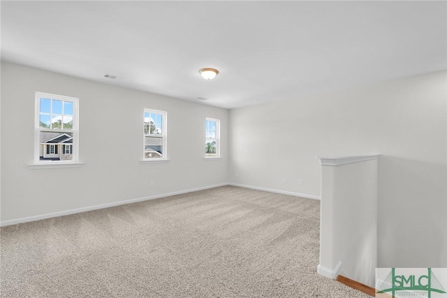 unfurnished room featuring a healthy amount of sunlight, baseboards, carpet, and visible vents