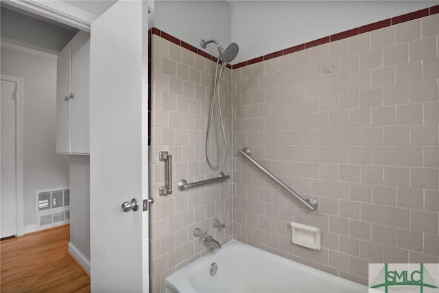 bathroom featuring visible vents, baseboards, shower / tub combination, and wood finished floors
