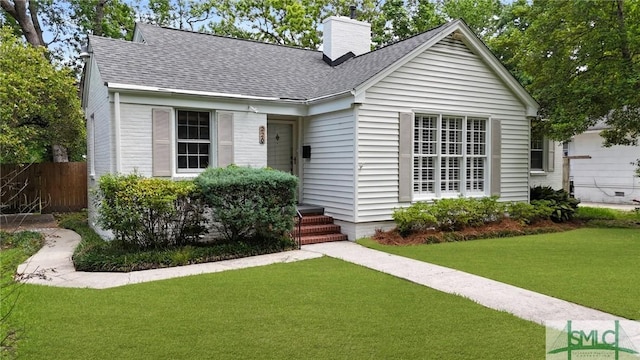 view of front of house with a shingled roof, fence, a front yard, and a chimney