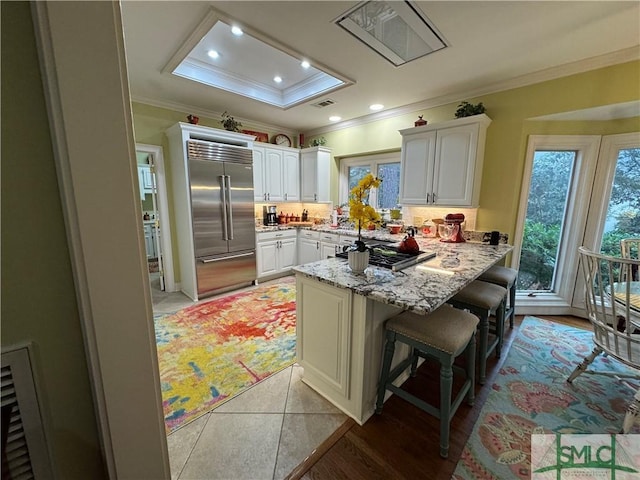 kitchen featuring crown molding, a wealth of natural light, stainless steel built in fridge, and gas stovetop
