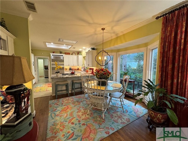 dining room with crown molding, light wood-type flooring, visible vents, and an inviting chandelier