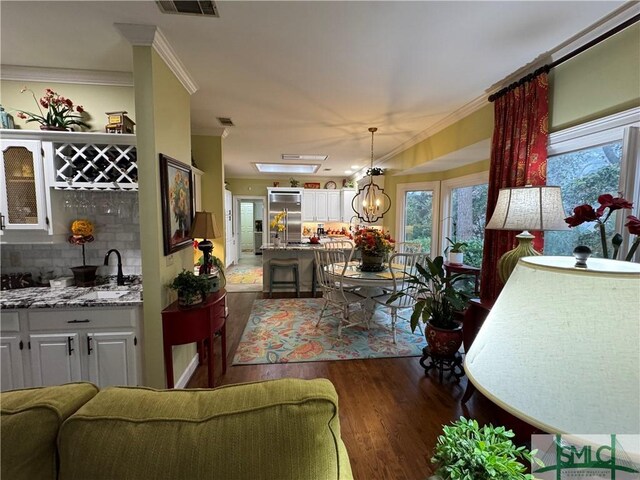 living area featuring ornamental molding, plenty of natural light, and dark wood-type flooring