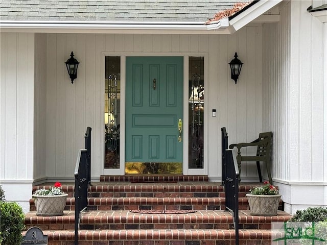 entrance to property with a shingled roof and a porch