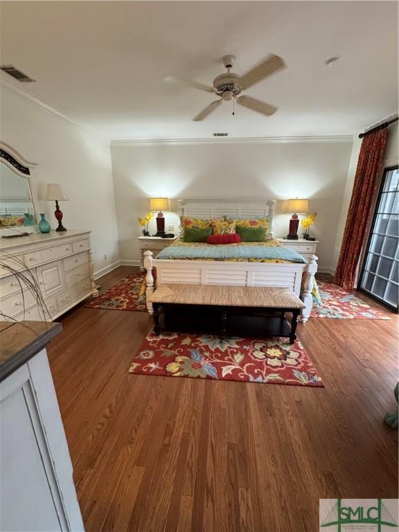 bedroom featuring baseboards, visible vents, crown molding, and wood finished floors