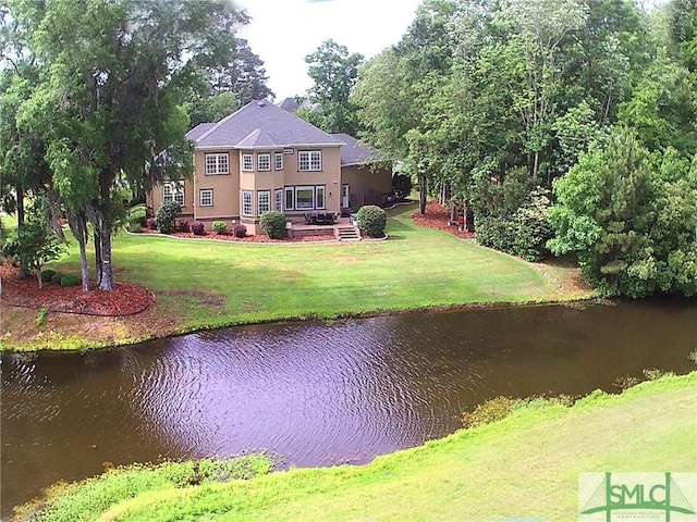back of house with a water view, a yard, and stucco siding