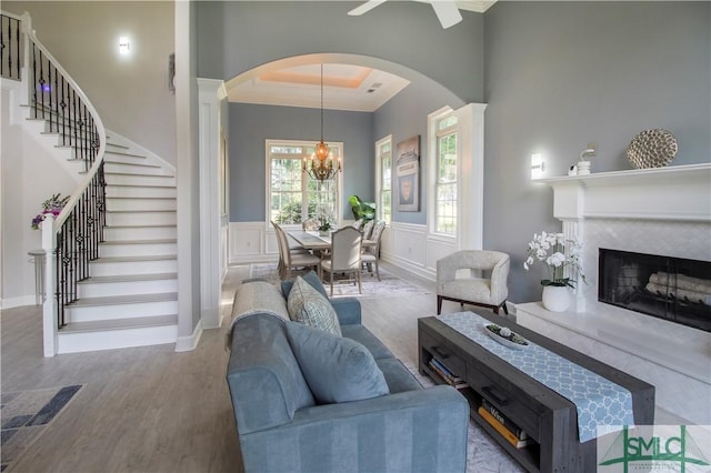 living room featuring arched walkways, stairs, wood finished floors, and a fireplace