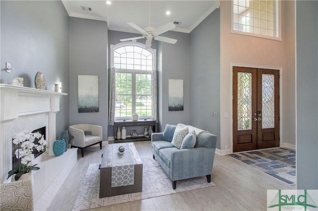 living area featuring crown molding, visible vents, wood finished floors, and a towering ceiling