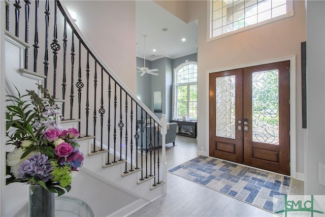 entrance foyer with ceiling fan, french doors, wood finished floors, a towering ceiling, and stairway
