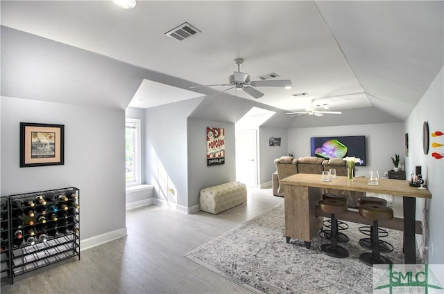 home office featuring ceiling fan, baseboards, wood finished floors, vaulted ceiling, and visible vents