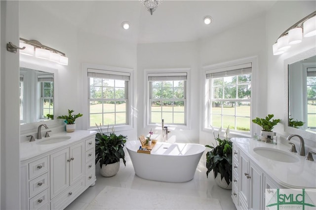 full bathroom with two vanities, a healthy amount of sunlight, and a sink