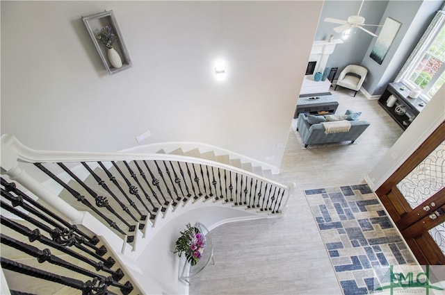 stairway with a ceiling fan and wood finished floors