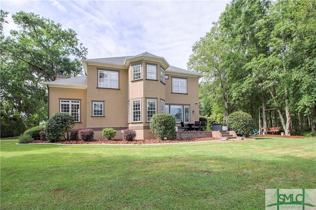 back of house with a lawn, stucco siding, and a patio
