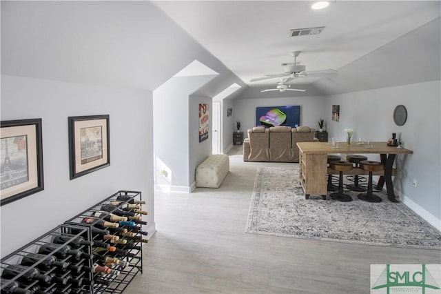 rec room featuring visible vents, a ceiling fan, baseboards, wood finished floors, and vaulted ceiling