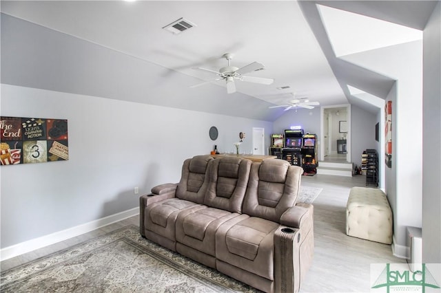 living area featuring visible vents, lofted ceiling, baseboards, ceiling fan, and light wood-type flooring
