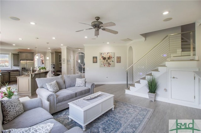 living room with a ceiling fan, arched walkways, stairs, wood finished floors, and recessed lighting