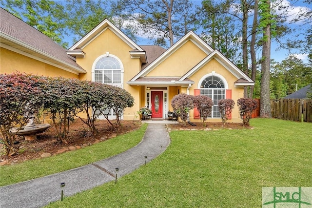 view of front of home with fence, stucco siding, and a front yard