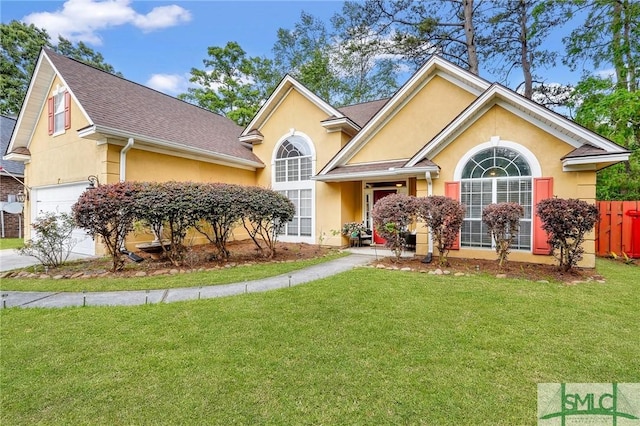 view of front of home featuring a garage, stucco siding, a front yard, and fence
