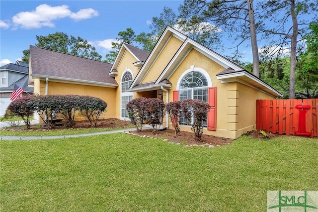 view of front of house featuring fence, stucco siding, and a front lawn