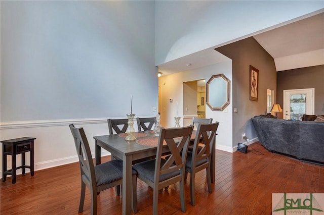 dining space with baseboards, hardwood / wood-style flooring, and lofted ceiling