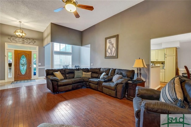 living room featuring baseboards, a high ceiling, ceiling fan, and light wood-style floors