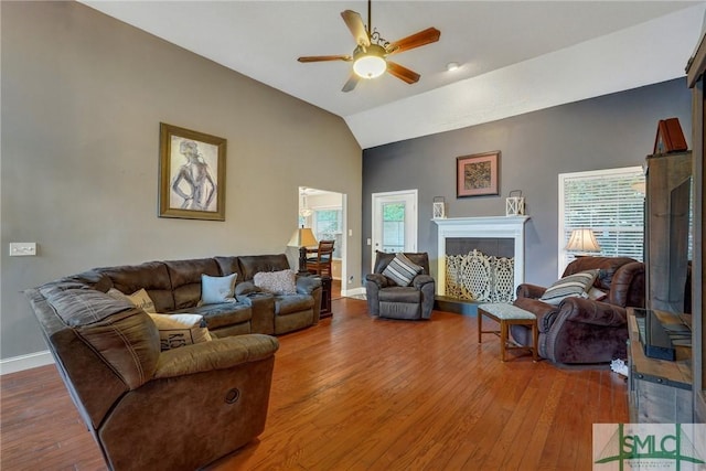 living room featuring wood-type flooring, a ceiling fan, a wealth of natural light, and vaulted ceiling